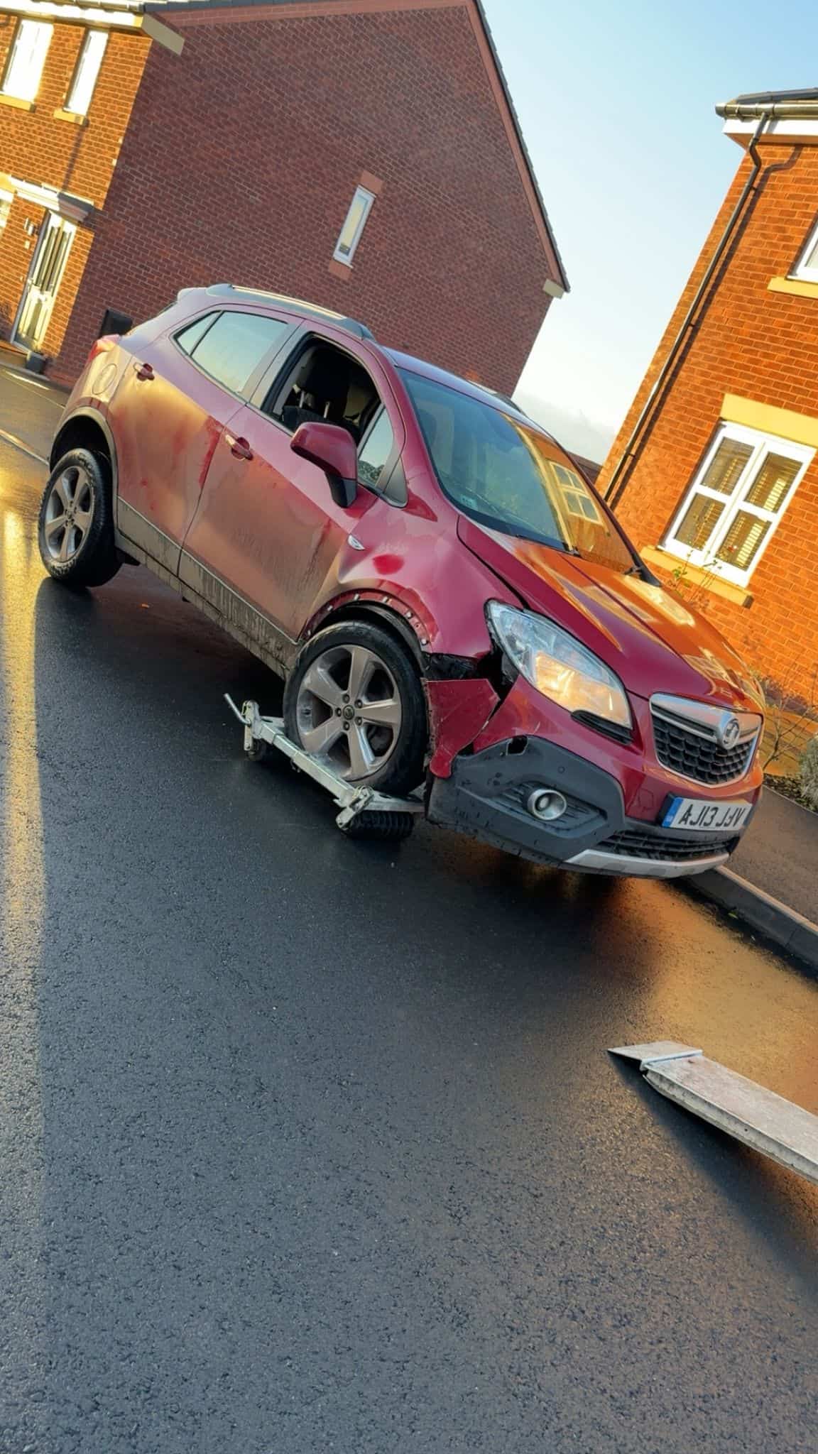 Accident involving a red vehicle with front-end damage on a quiet neighbourhood road.