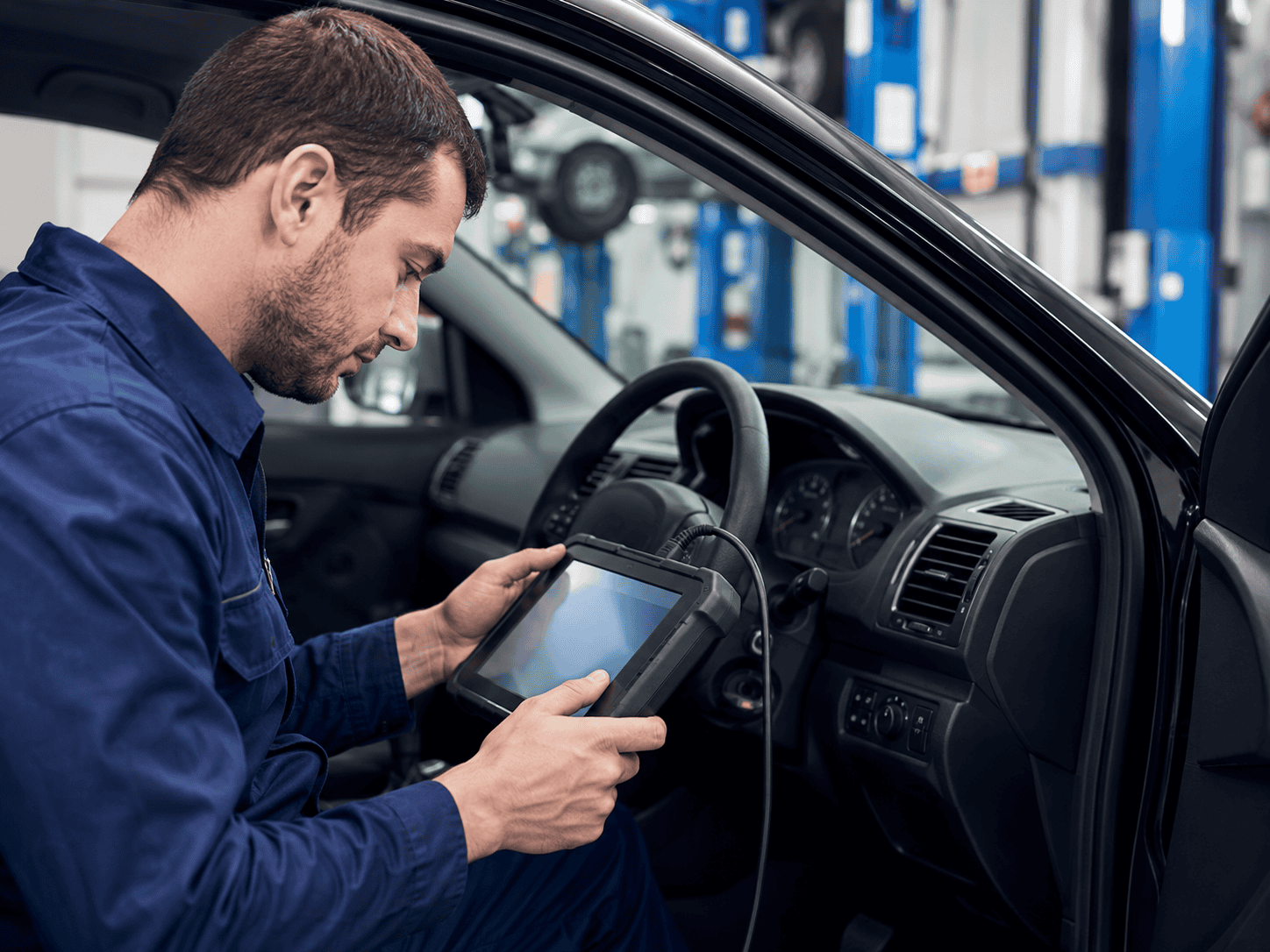 Automotive technician using diagnostic tool in vehicle in Telford area.